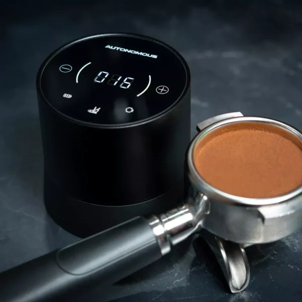 Autonomous Tamper next to espresso portafilter filled with ground coffee